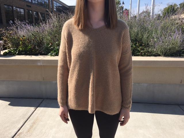 Emily Tomkinson is wearing a caramel colored sweater, perfect for fall